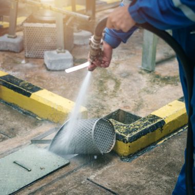 Worker cleaning bucket strainer in industrial plant